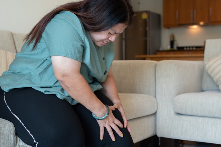 Woman holding her knee grimacing in pain