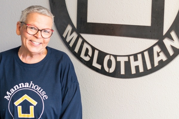 Sissy Franklin smiling for a photo in front of a sign that says "Midlothian" after her treatment for breast cancer