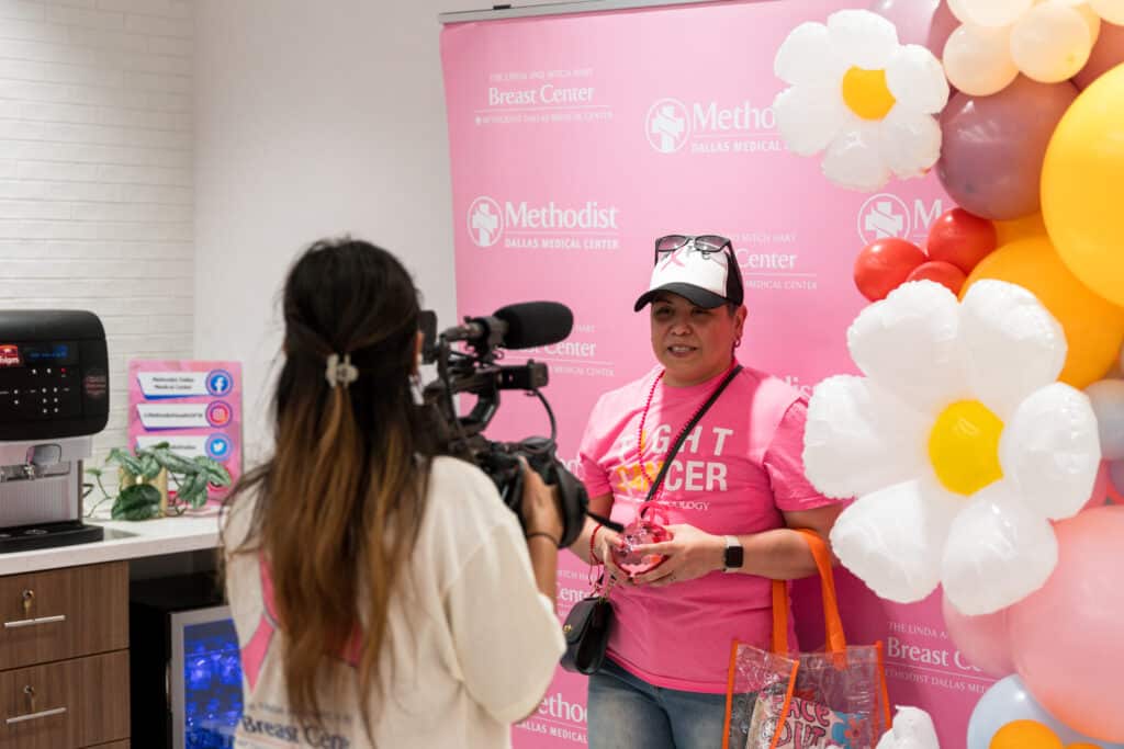 Innocente Escamilla in front of a pink backdrop and being photographed at an event