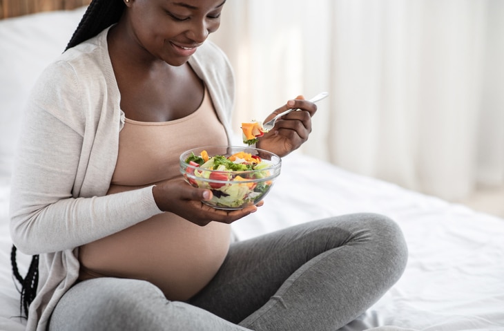 A pregnant woman eating a salad