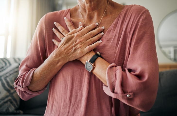 A woman in a blush blouse crossing her hands across her chest with her palms facing inward