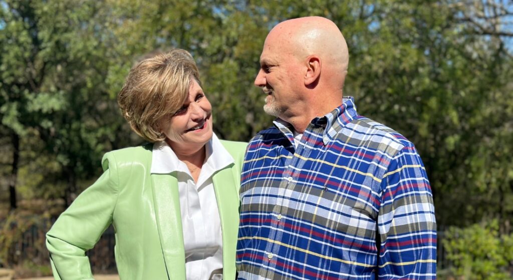 An older couple named Mark and Sandra Stewart photographed outside and smiling at each other, used to explain the story of how a broken ankle led Mark back to the same hospital that he got heart care