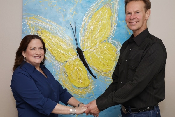 Bob and Julia Helland photographed in front of a yellow butterfly mural
