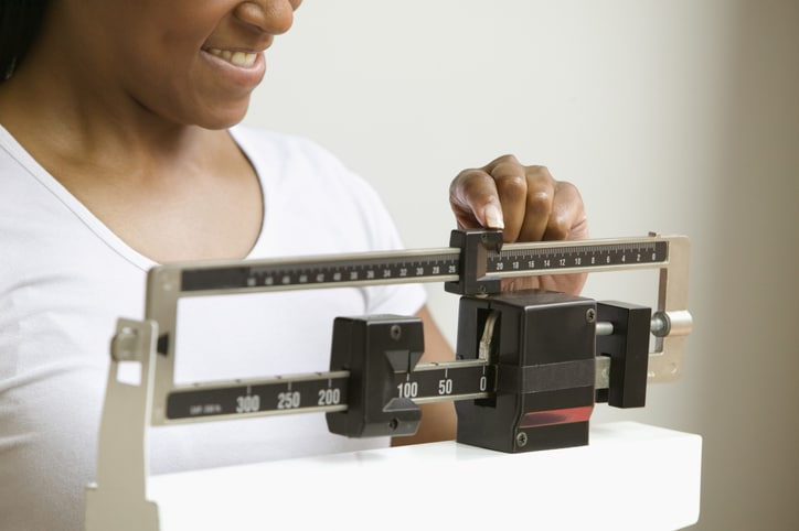 A woman smiling and looking at a scale