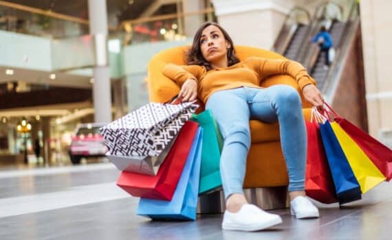 An exhausted woman with many shopping bags takes a break in a shopping mall.