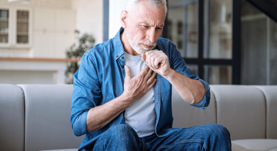 A man reaching a closed hand toward his mouth as if he were coughing, used to explain esophagus cancer and Barrett's esophagus