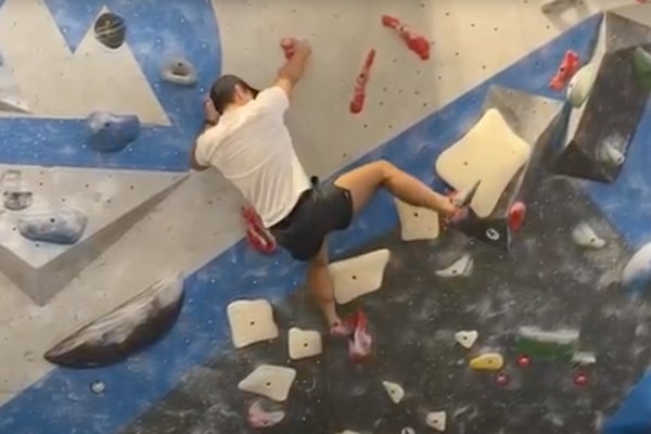 A man climbs a wall at an indoor rock-climbing facility.