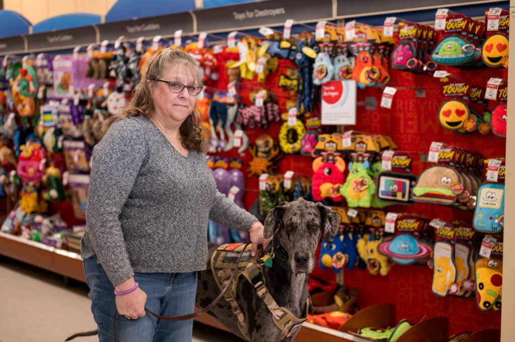 A woman and her dog stand in a pet supply store.