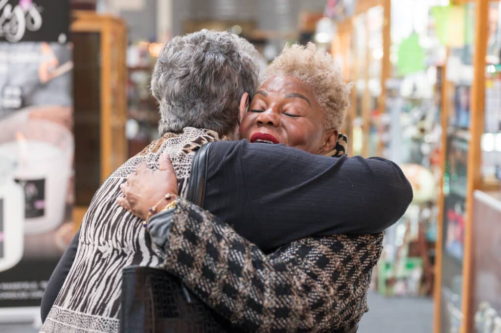 Debra Martin-ez and her friend Gloria Williams embracing in a hug.