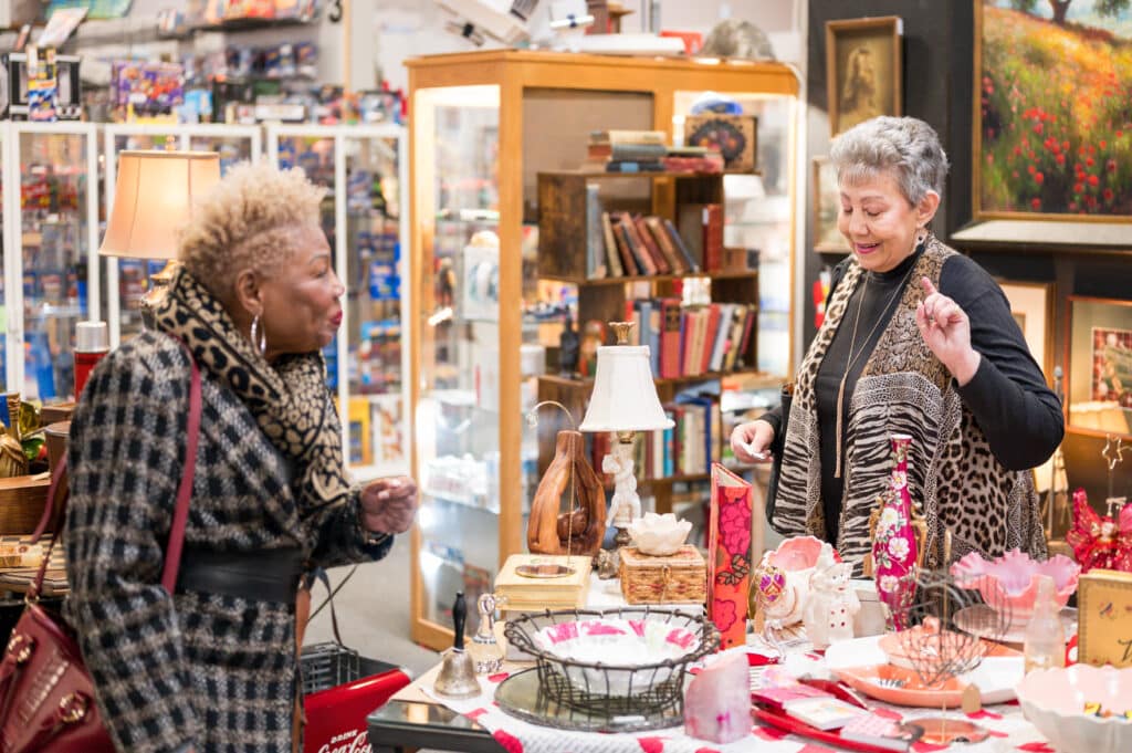 Debra Martin-ez and her friend Gloria Williams looking toward a table at an antique shop.