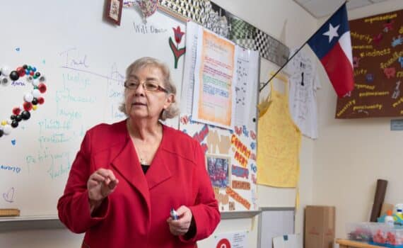 Educator Eugenia Jameson wearing a red blazer and teaching in a classroom, used to explain her recovery after heart valve surgery