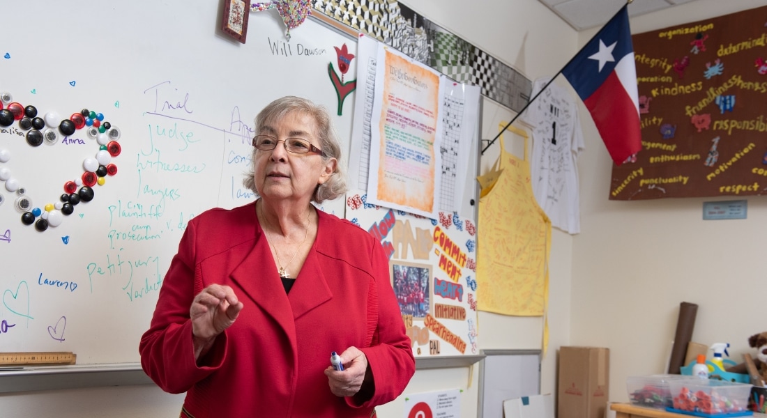 Educator Eugenia Jameson wearing a red blazer and teaching in a classroom, used to explain her recovery after heart valve surgery