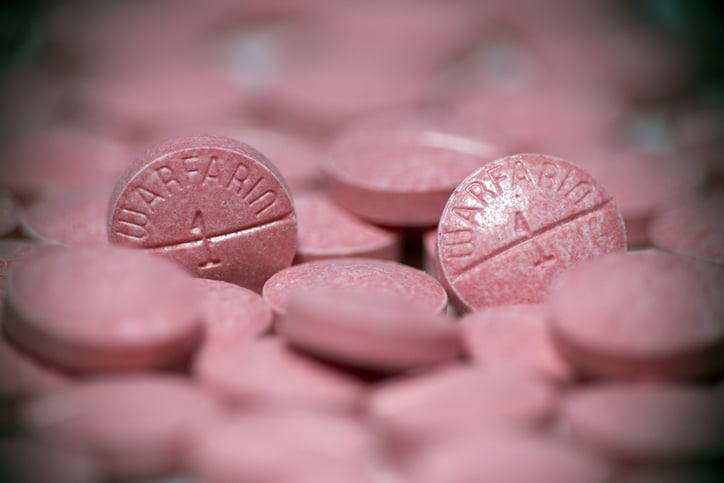 A close up photo of a pile of pink pills with the text "warafarin" and the number one on them