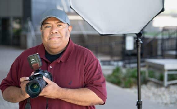 Cesar Zapata posing for a photograph while holding his camera