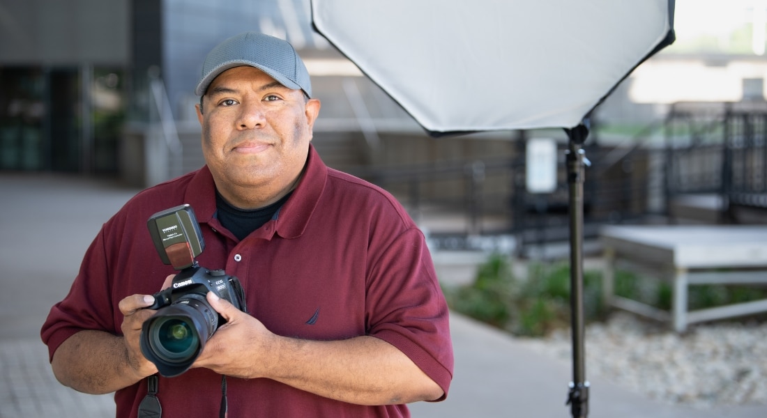 Cesar Zapata posing for a photograph while holding his camera