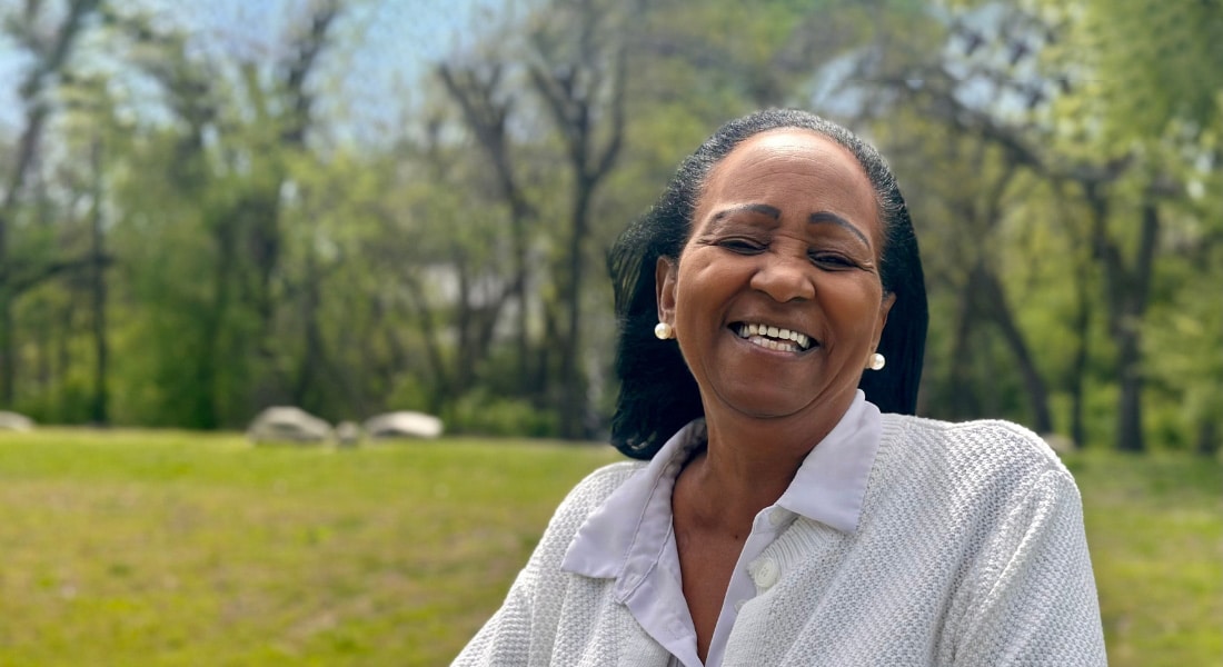 Crystal Walker sitting outside in front of a field and smiling toward the camera
