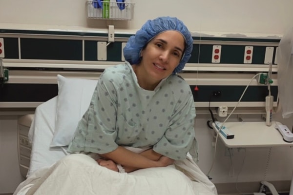 Erika Mora in scrubs and hospital clothing while in a hospital bed