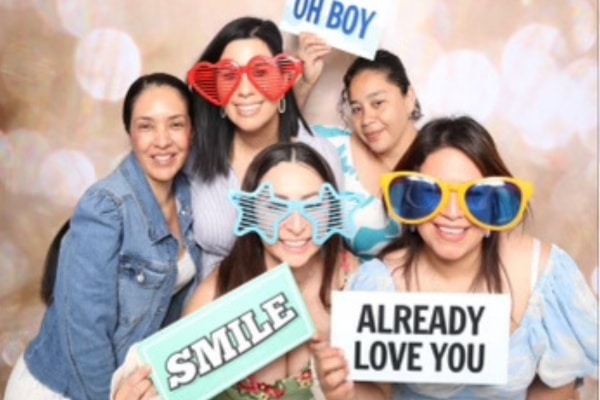 A group of women, including Erika Mora, photographed with posters with inspiration statements, like "Smile" and "Already love you" while wearing oversized colorful classes