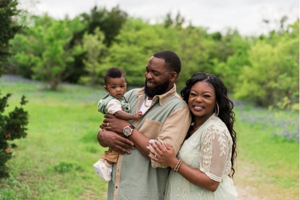 LaTeisha Young, her husband Jeromey, and their newborn Mason photographed outside in an editorial or portrait style while wearing green and brown complementing outfits