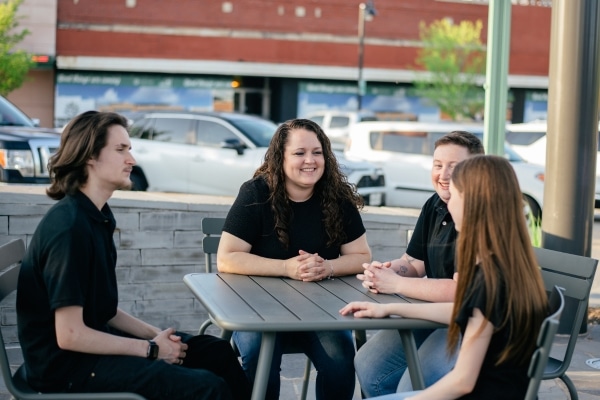 A woman named Amanda Hopkins photographed with her children, all wearing black shirts, and another person at a table