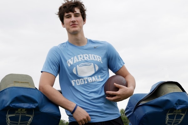 Liberty Christian wide receiver Henri DeRoche photographed wearing a school Warrior football shirt and holding a football at his side