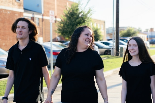 A woman named Amanda Hopkins photographed with her two children, all wearing black shirts, following her liver tumor and treatment
