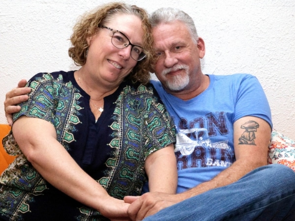 Tim and Katherine Odom photographed hugging and sitting on a couch