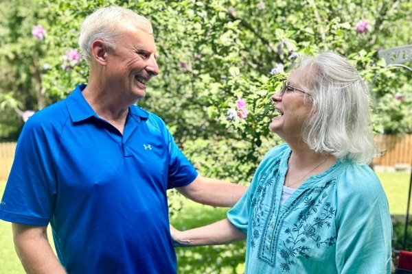 A man and woman smile at each other in front of a flowering tree.