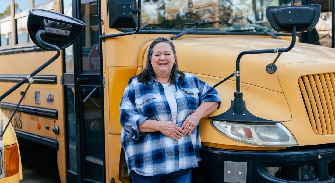 Delonda Faltesek standing beside a school bus at Oak Park School.