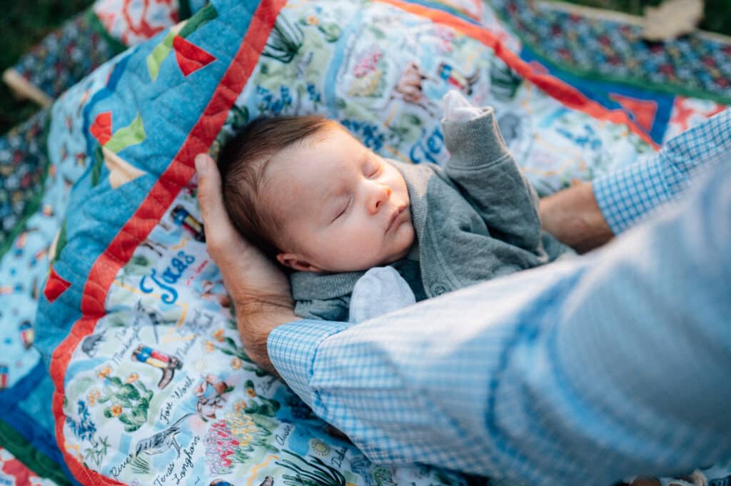 Michael Farrah lays his son Miles down on a blanket outdoors.