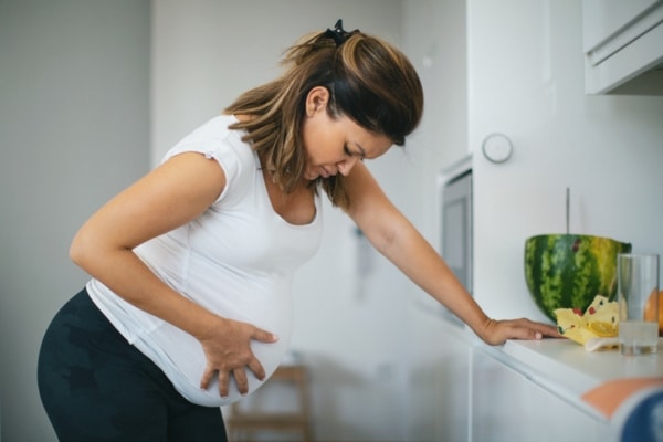 Pregnant woman leans on a counter to ease the pains of her contractions.