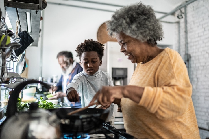 Grandson helping his grandmother cooking at home.