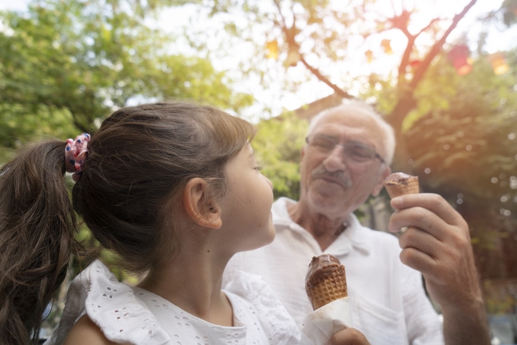 Granddaughter and grandfather eating ice cream in cones.