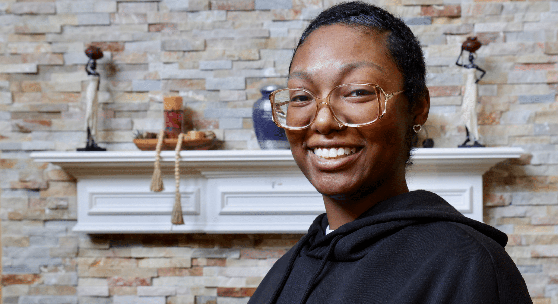 Kiana Hill poses in front of her fireplace mantle with a smile.