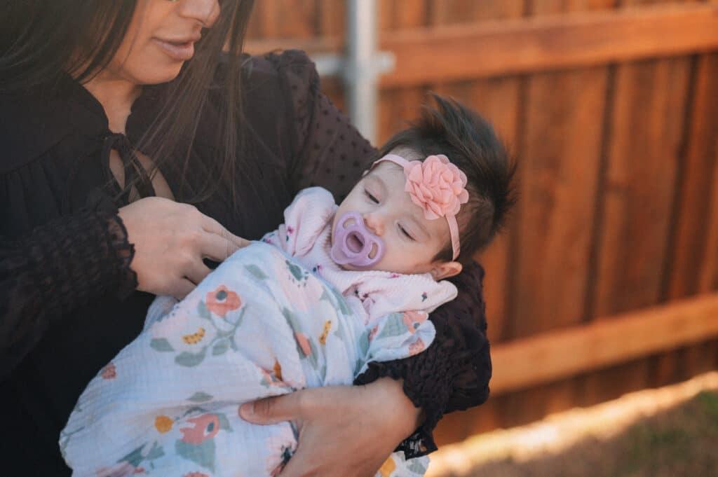 Kiran Lalani holds her newborn, Mila Grace, outside her home in Ennis.