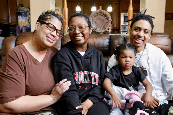 Kiana poses with her mom, Katonya, brother, Greg, and two-year-old daughter, Zoe. on their couch.