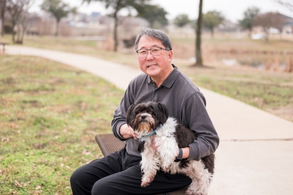 Heart patient Richard Chin sits with his dog at a park near his Sachse home.