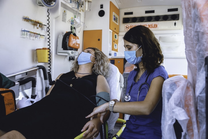 A patient wearing a medical mask receiving care from a medical professional, used to explain women and heart attacks