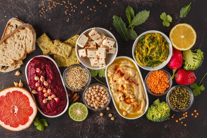 A spread shows tofu, hummus, green pea dip, among other vegetables high in protein. 