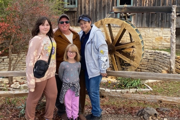 Transplant patient Joy Salvatore and her partner Sharon Kerr stand in front of a water mill with their granddaughters.