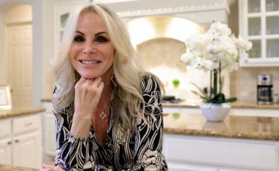 Michelle Davis poses in her kitchen with her hand under her chin as she smiles.