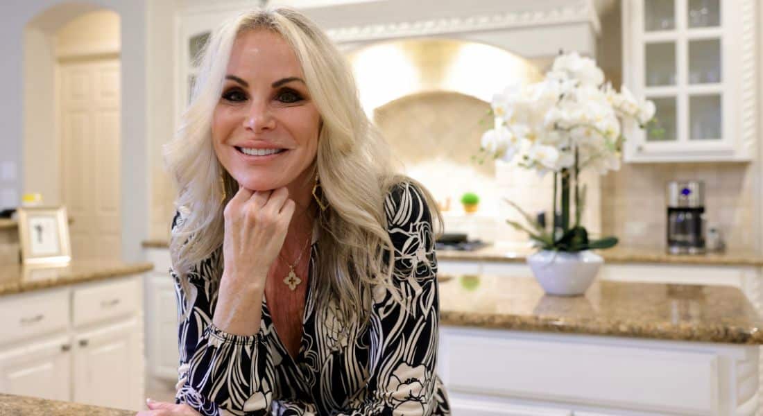 Michelle Davis poses in her kitchen with her hand under her chin as she smiles.