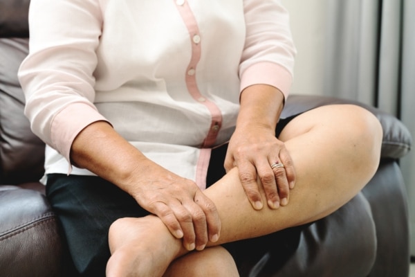 An unrecognizable senior woman rubs her calf while experiencing a blood clot.