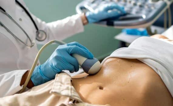 A doctor performs an ultrasound to detect pancreatic cancer in a female patient.