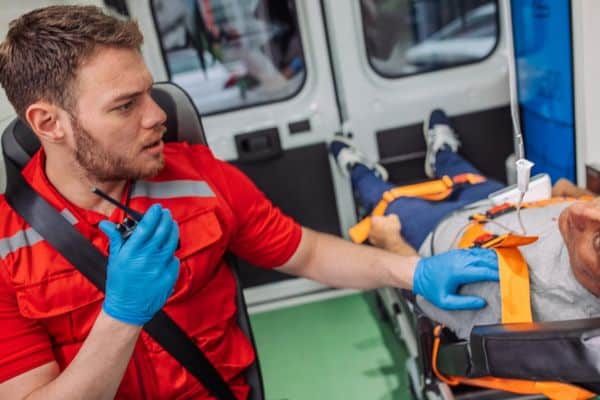 A paramedic talks on the radio while speaking to a patient in the back of an ambulance.