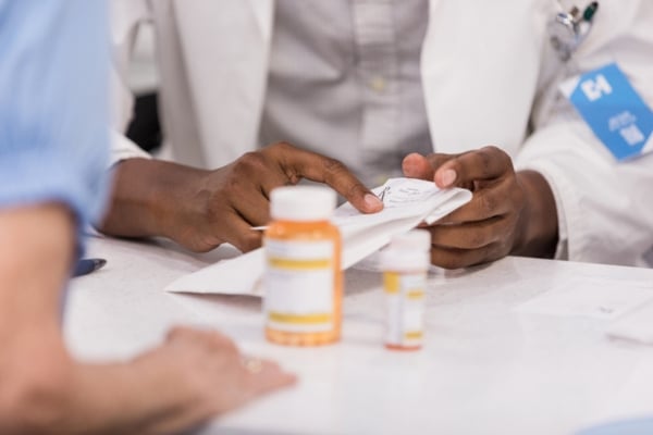 A pharmacist consults with a patient over the counter at a pharmacy.
