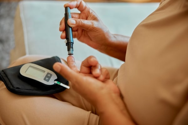 A diabetes patients tests her blood pressure by pricking her finger.