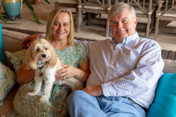 Rebecca and Jeff Landreth sit on a couch with their dog.