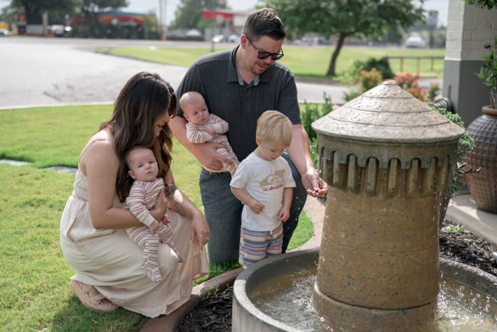 Alexia and Austin Coleman pose next to a fountain with their son Dawson and twins Henry and Harvey.