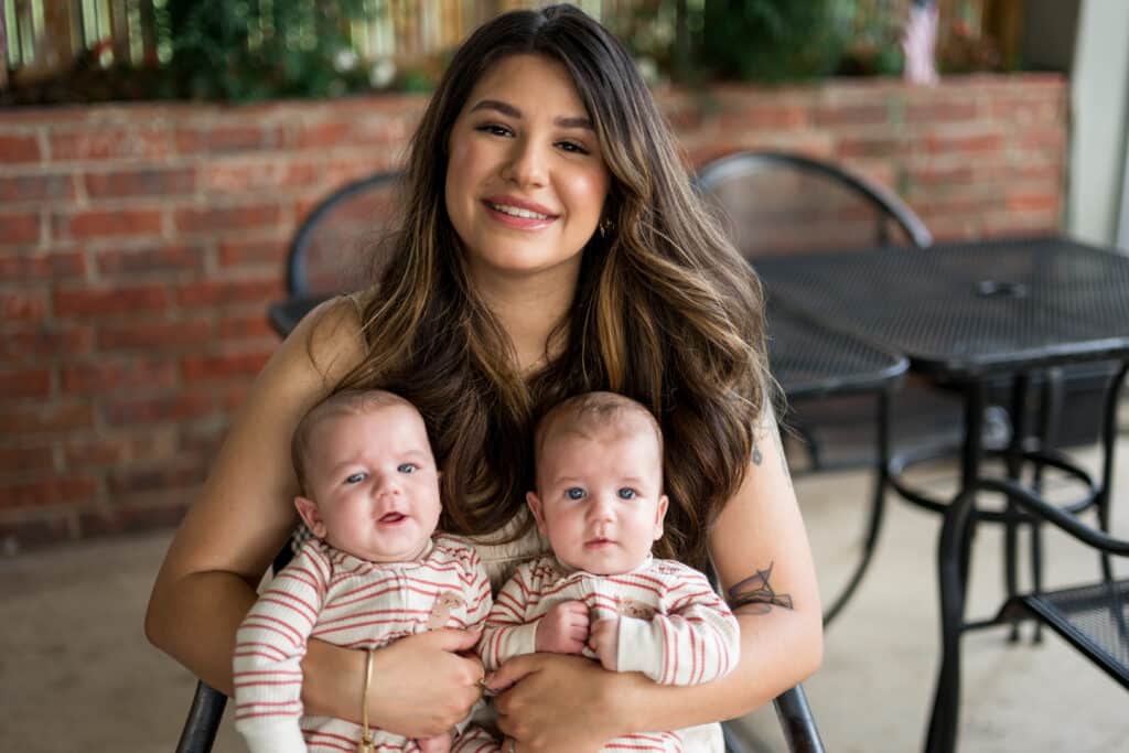 Alexia Coleman holds her twin boys sitting outside on a patio.